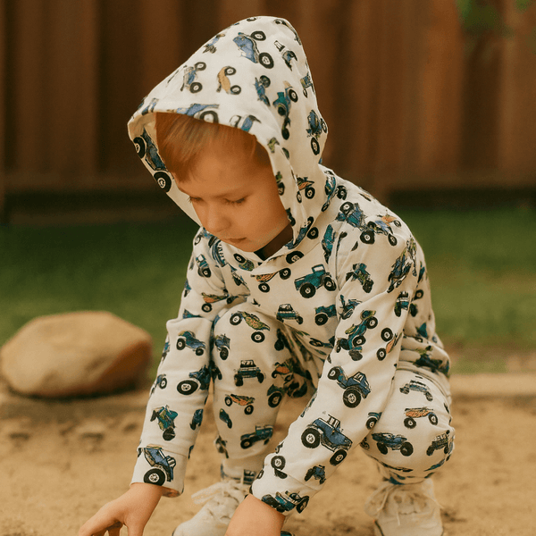 Child wearing a hoodie with truck patterns outdoors