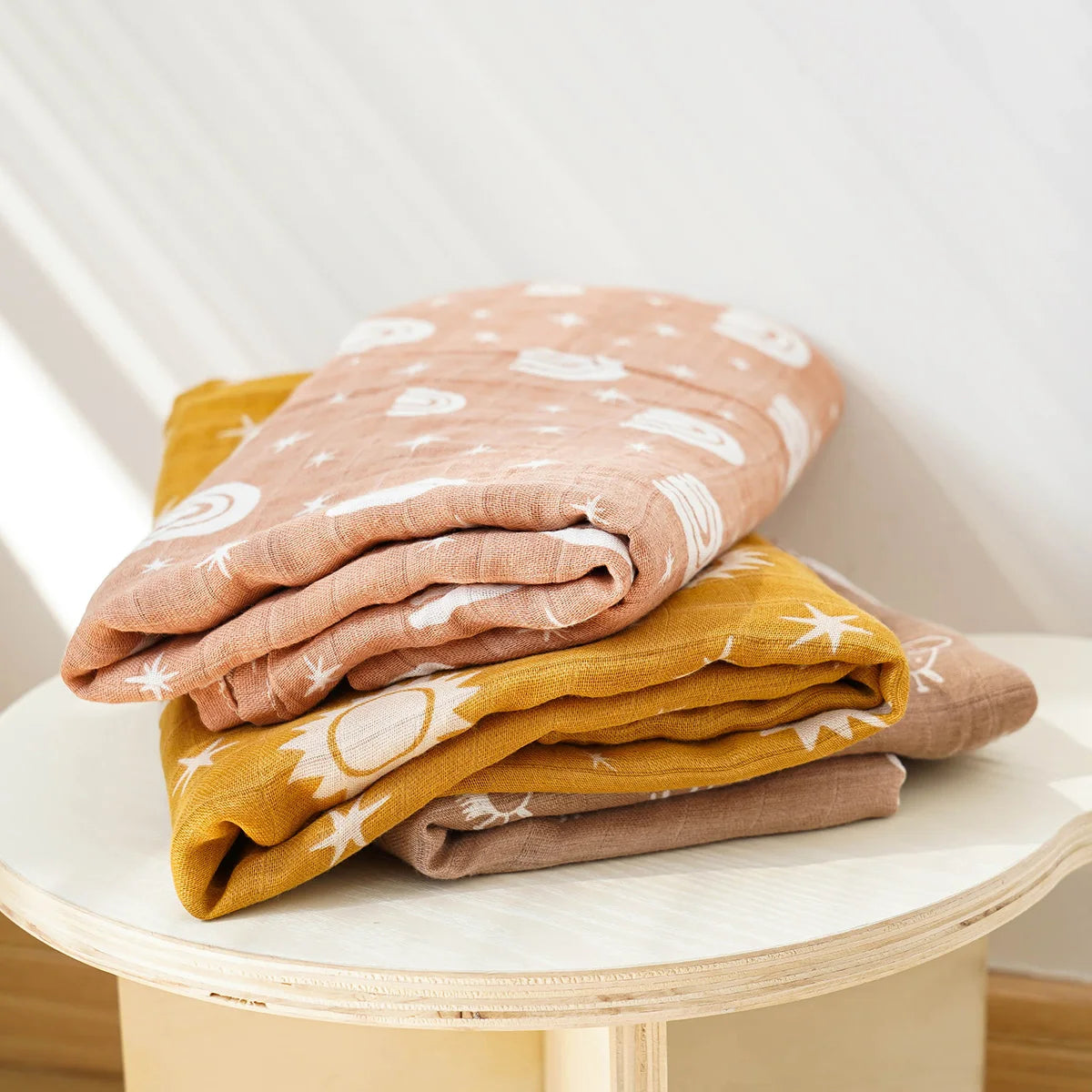 Set of mustard and blush muslin swaddle blankets for babies with sun and cloud patterns