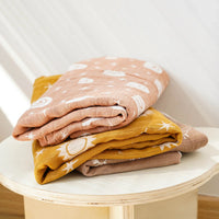 Set of mustard and blush muslin swaddle blankets for babies with sun and cloud patterns