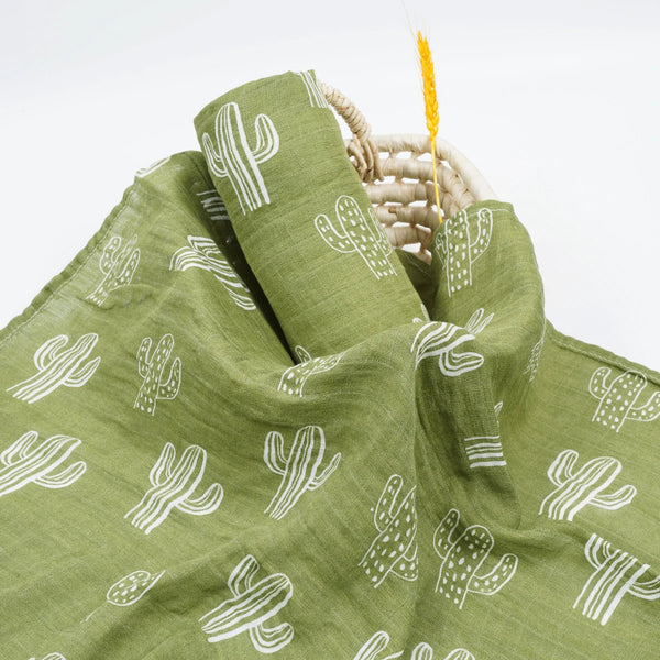 Green muslin swaddle with white cactus print for babies, lightweight breathable fabric