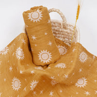 Golden yellow muslin swaddle with white sun and star print for babies in a woven basket