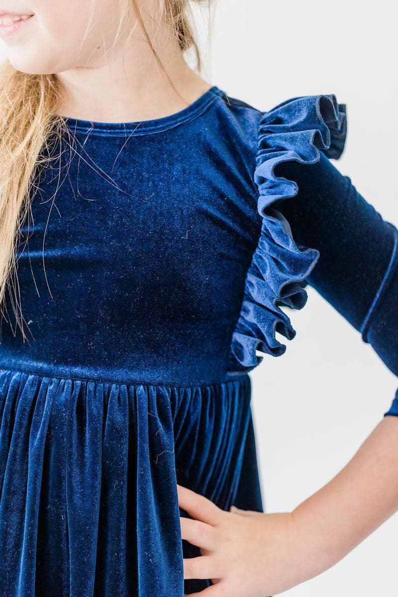 young girl wearing navy velvet ruffle dress for girls with hand on hip posing