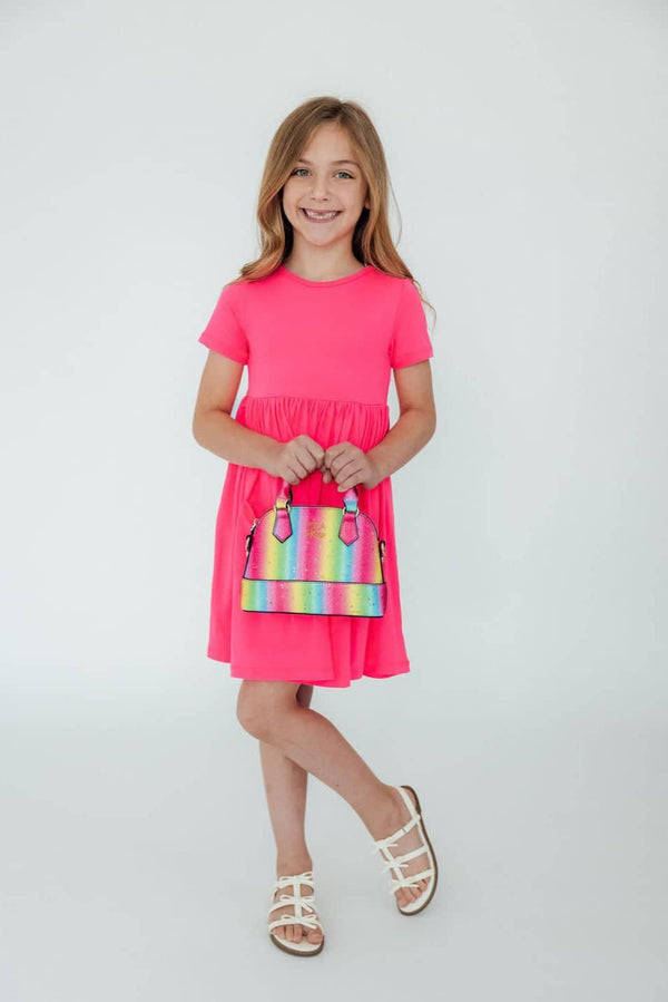 girl wearing neon pink girls twirl dress holding colorful handbag standing and smiling