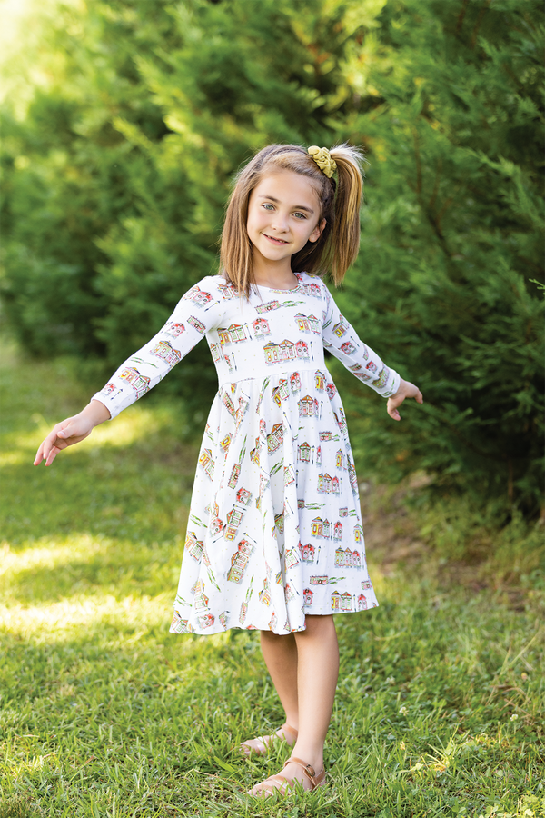 Bayou Wonderland Organic Cotton Christmas Dress for Kids: girl in white house-print dress with knee-length full skirt.