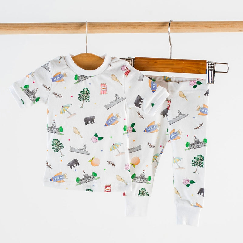 Alabama Kids Organic Cotton Pajamas, white two-piece set with rockets, trees, and buildings print.