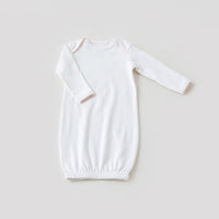 White newborn take me home gown with baby pink trim, featuring long sleeves and an elastic hem for elegant, easy diaper access.