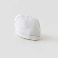 White newborn beanie hat with delicate baby pink stitched trim, part of the Take Me Home Set.
