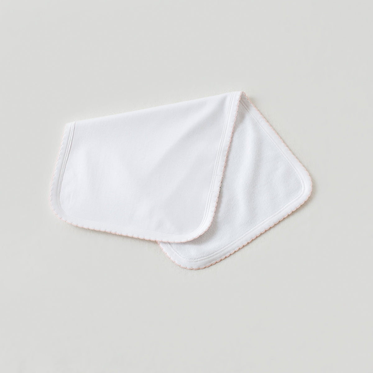 White newborn take me home swaddle blanket with soft baby pink trim for a sweet and elegant hospital outfit.