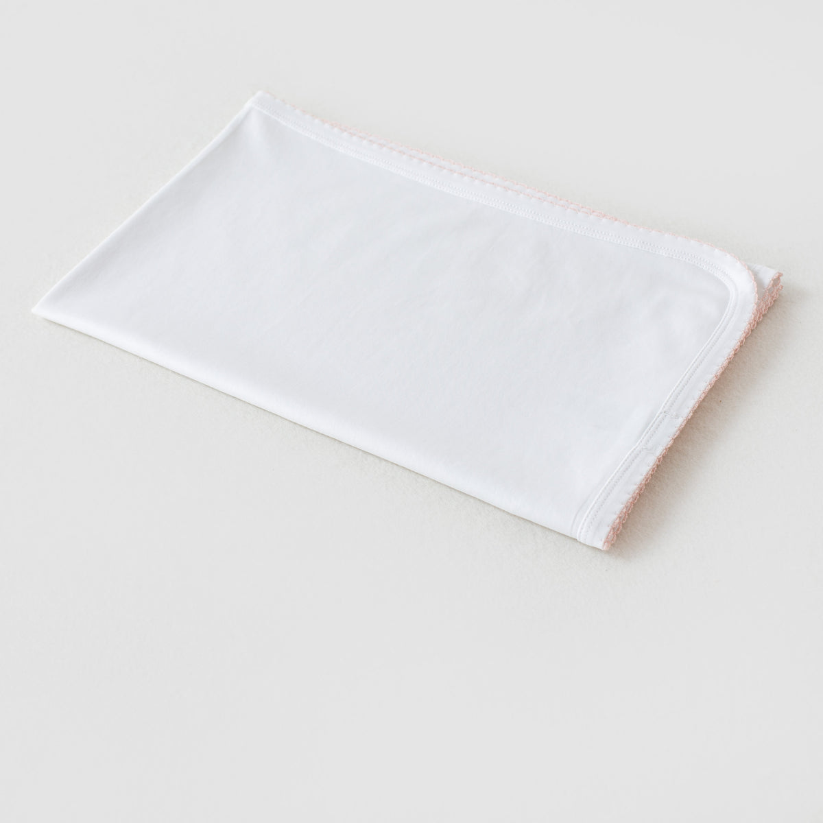 White newborn take me home swaddle blanket featuring delicate baby pink piping along the edges.