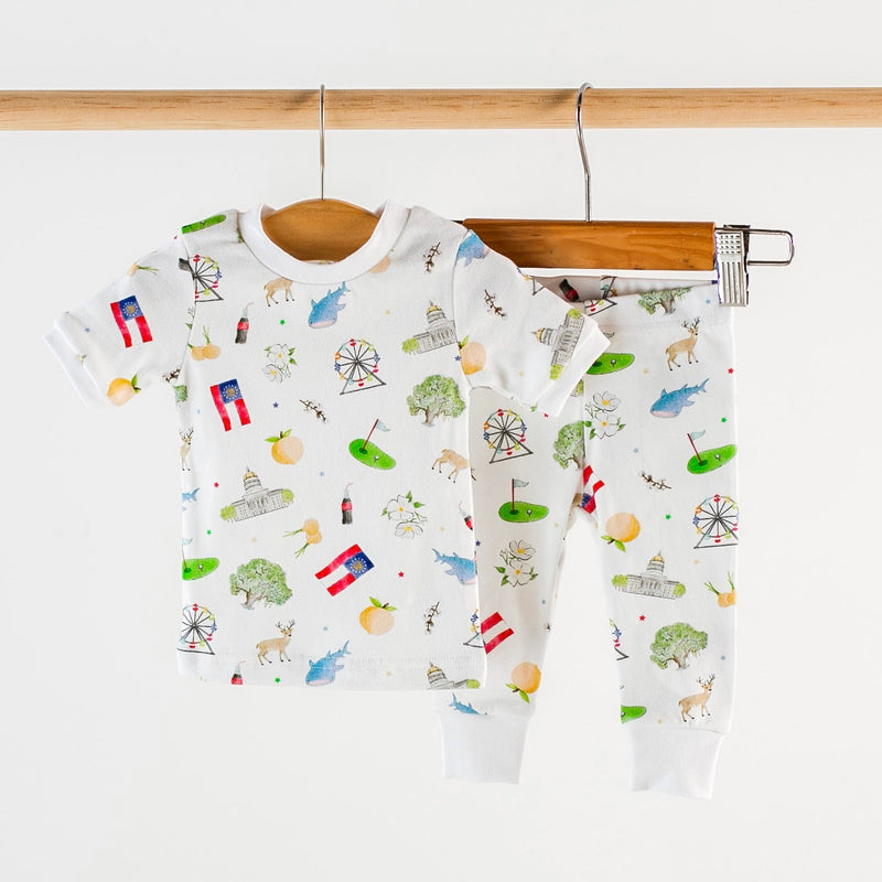 Georgia Kids Organic Cotton Pajamas two-piece set with whimsical prints hanging on a wooden rack