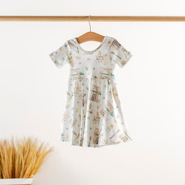 Powdered Sugar and Puppies kids dress on a wooden hanger; white organic cotton with playful dog print.