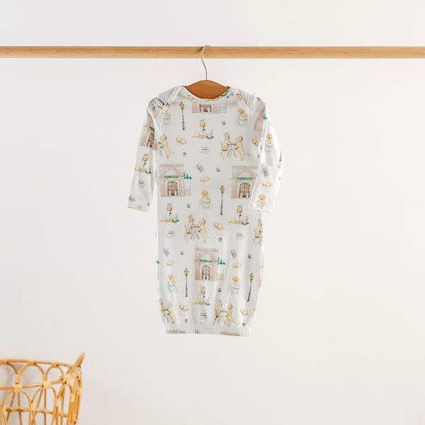 Baby onesie with a pattern of dogs hanging on a wooden hanger against a white background
