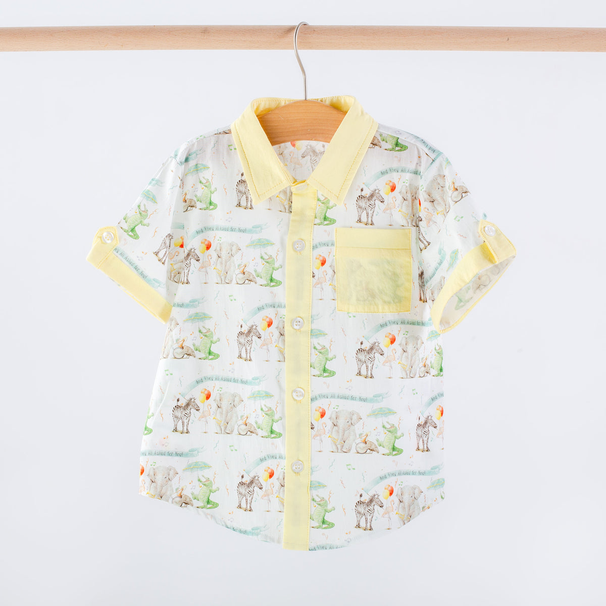Children's shirt with animal pattern and yellow accents on a hanger against a white background