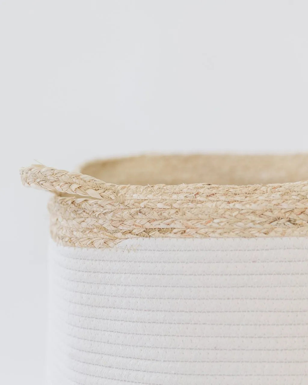 Close-up of cream rope laundry basket showing texture contrast between smooth white coils and rough natural fiber rim