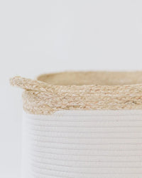 Close-up of cream rope laundry basket showing texture contrast between smooth white coils and rough natural fiber rim