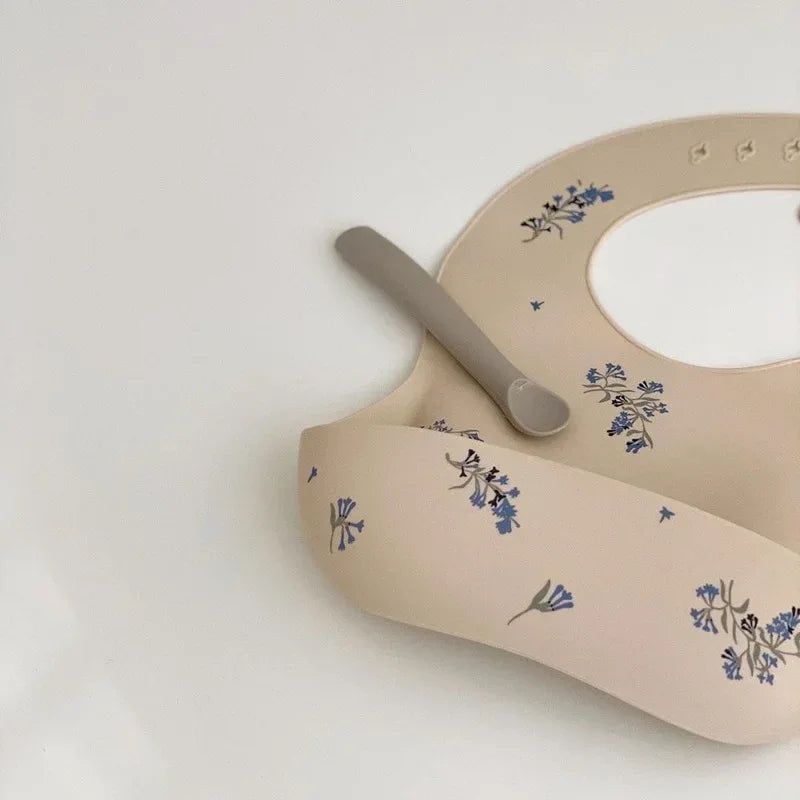 Beige waterproof baby bibs with blue floral pattern and adjustable neck for infants and toddlers