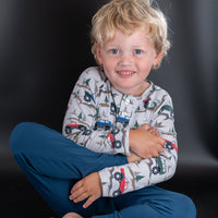 Boy wearing soft raglan henley with monster truck and tree print. Buttoned front placket designed for active play and sensitive skin comfort.