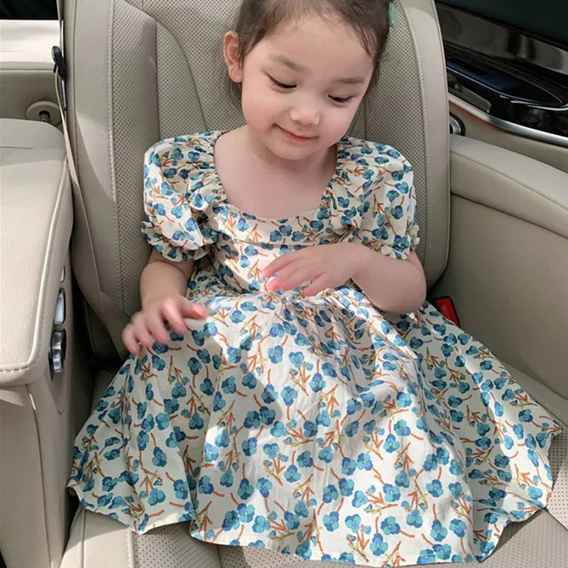 toddler girls white and blue floral party dress with puff sleeves sitting in car seat