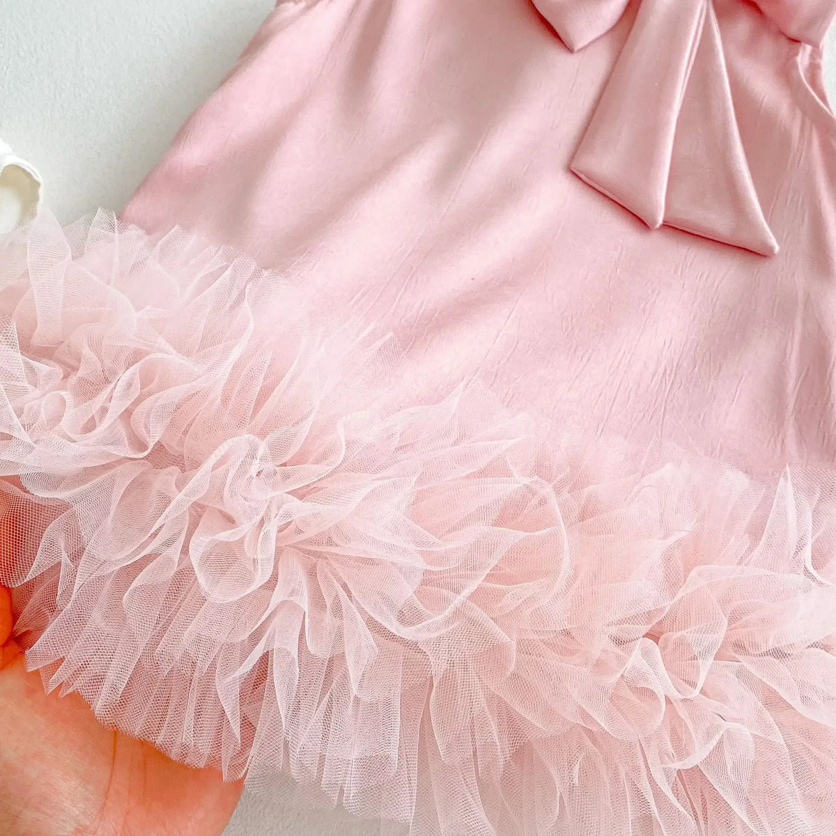 baby pink party dress for toddlers with bow detail and ruffled tulle hem