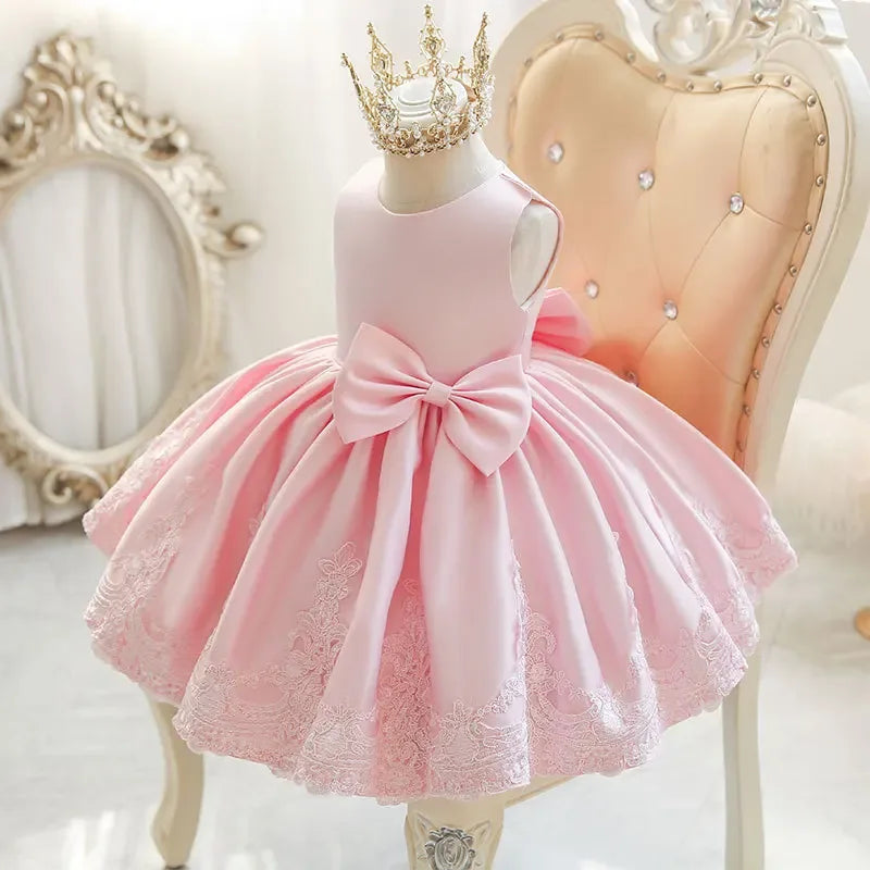 Sleeveless pink party dress for toddlers with large bow and lace hem detail