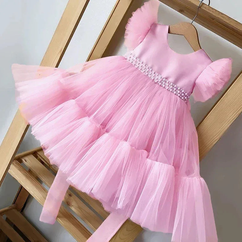 baby girls pink party dress with puff sleeves and pearl detail on waist, tulle skirt