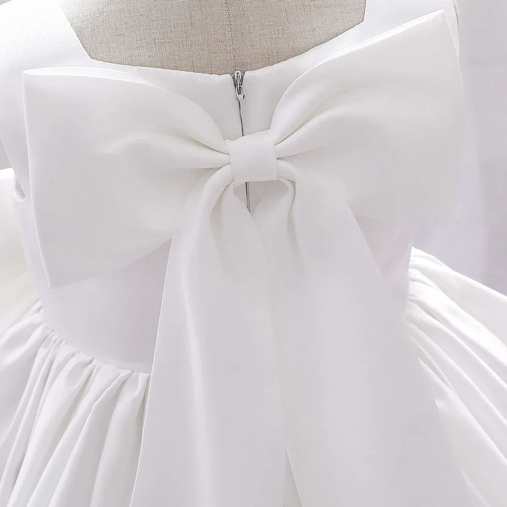 white baby party dress with large bow back detail and gathered skirt