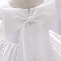 white baby party dress with large bow back detail and gathered skirt