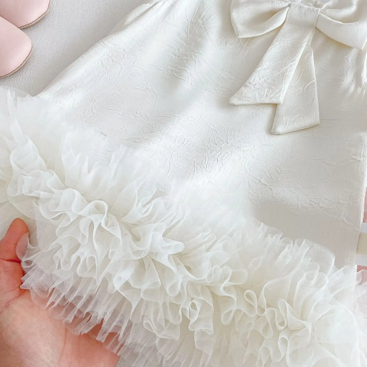 white baby party dress with bow detail and ruffled tulle hem for infants