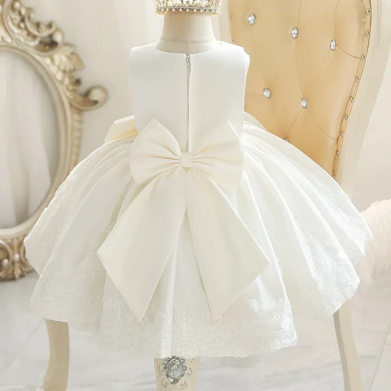 White party dress for babies with large bow and lace details, sleeveless design
