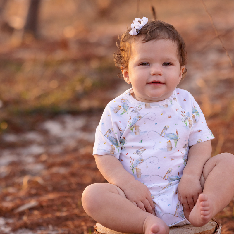 Baby wearing Pelican Bay Organic Cotton Onesie outdoors with coastal Louisiana print.