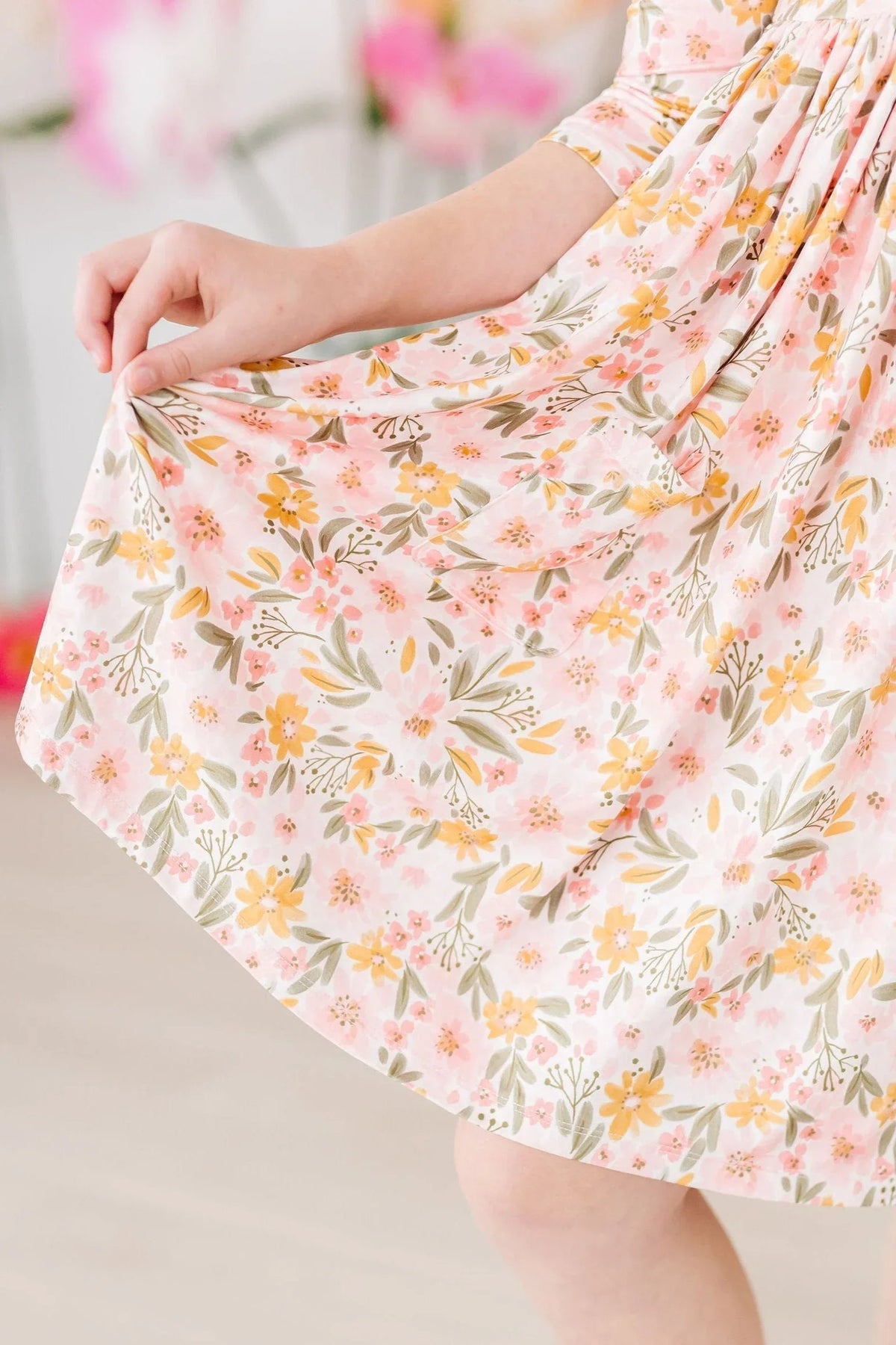 young girl wearing peach floral girls twirl dress holding skirt while twirling