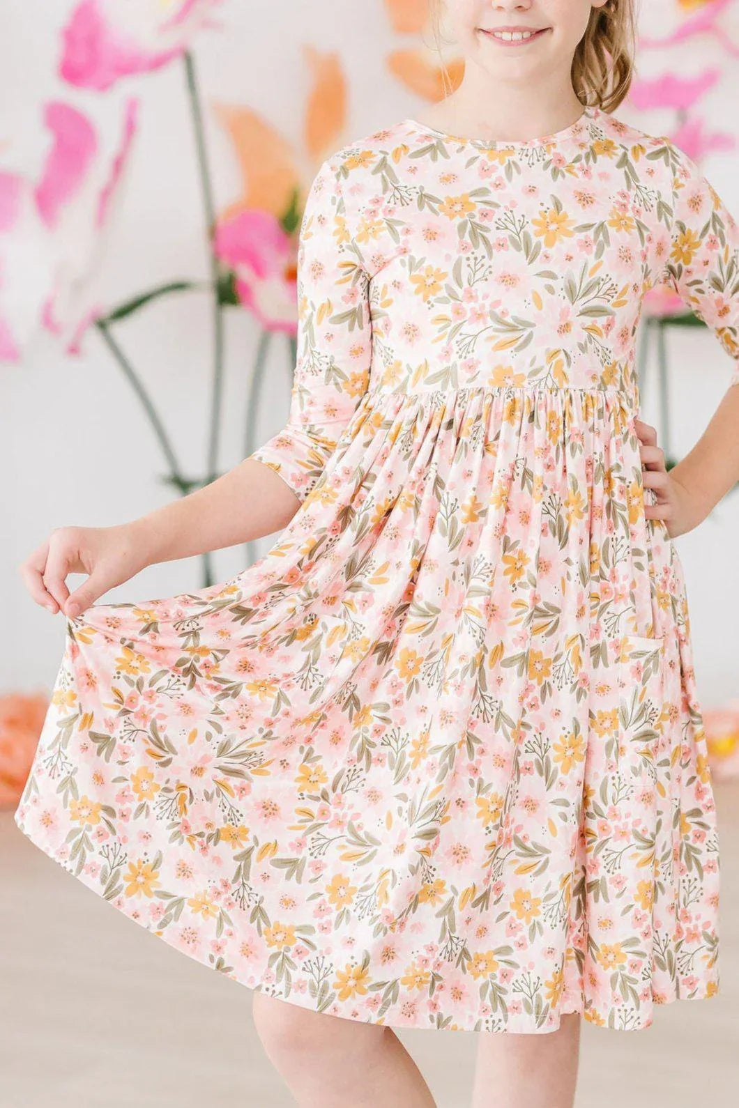 Girl wearing peach floral girls twirl dress 3/4 sleeves holding skirt while twirling