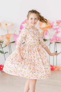 girl wearing peach floral girls twirl dress by Mila Rose spinning with a smile