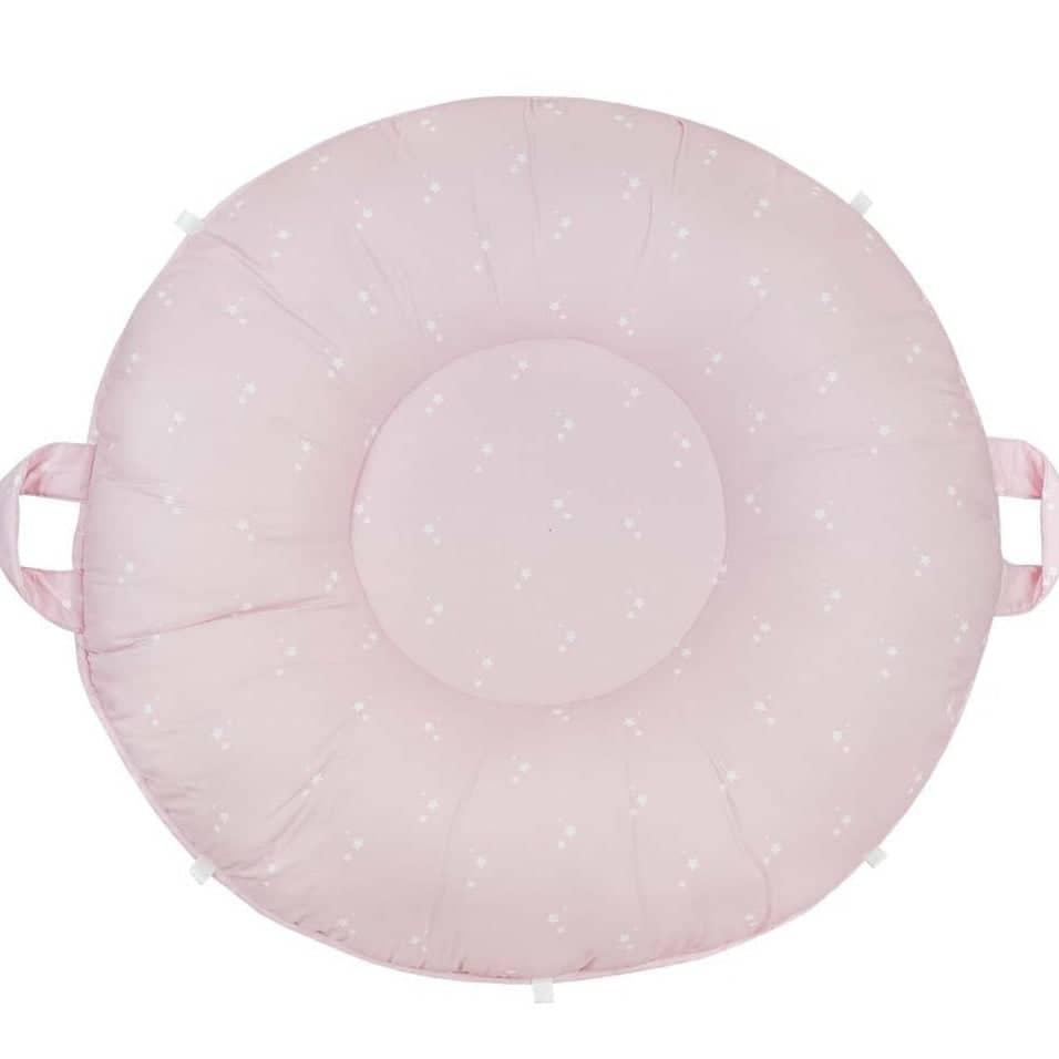 Pink floor cushion for toddlers made of soft fabric with small white star patterns and side handles