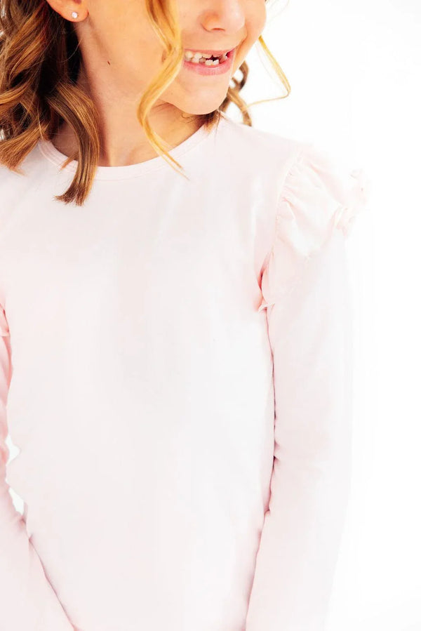 young girl wearing petal pink girls ruffle tee smiling and looking to the side