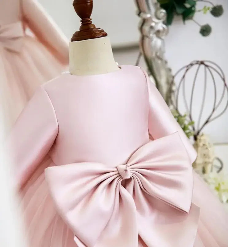 Pink baptism dress for girls with long sleeves and large bow detail on the back