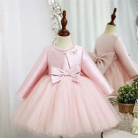 pink baptism dress for girls with long sleeves, pearl neckline, and large bow detail