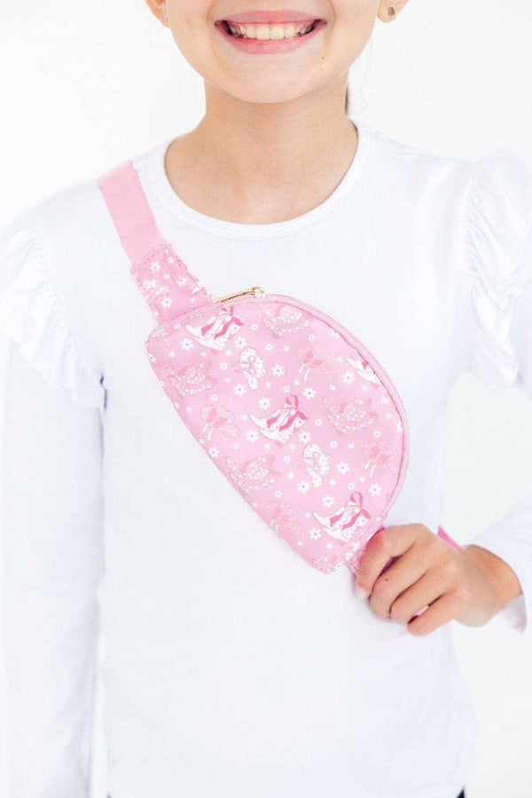 young girl wearing pink belt bag for little girls with floral and bow print across chest