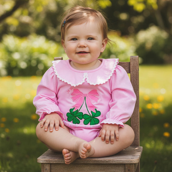 Baby wearing pink embroidered baby bubble romper made of soft cotton with clover and bow design