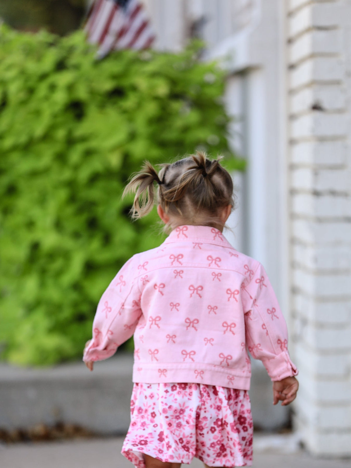 Toddler wearing pink girls butterfly denim jacket by Rylee Faith Designs with bow print and long sleeves