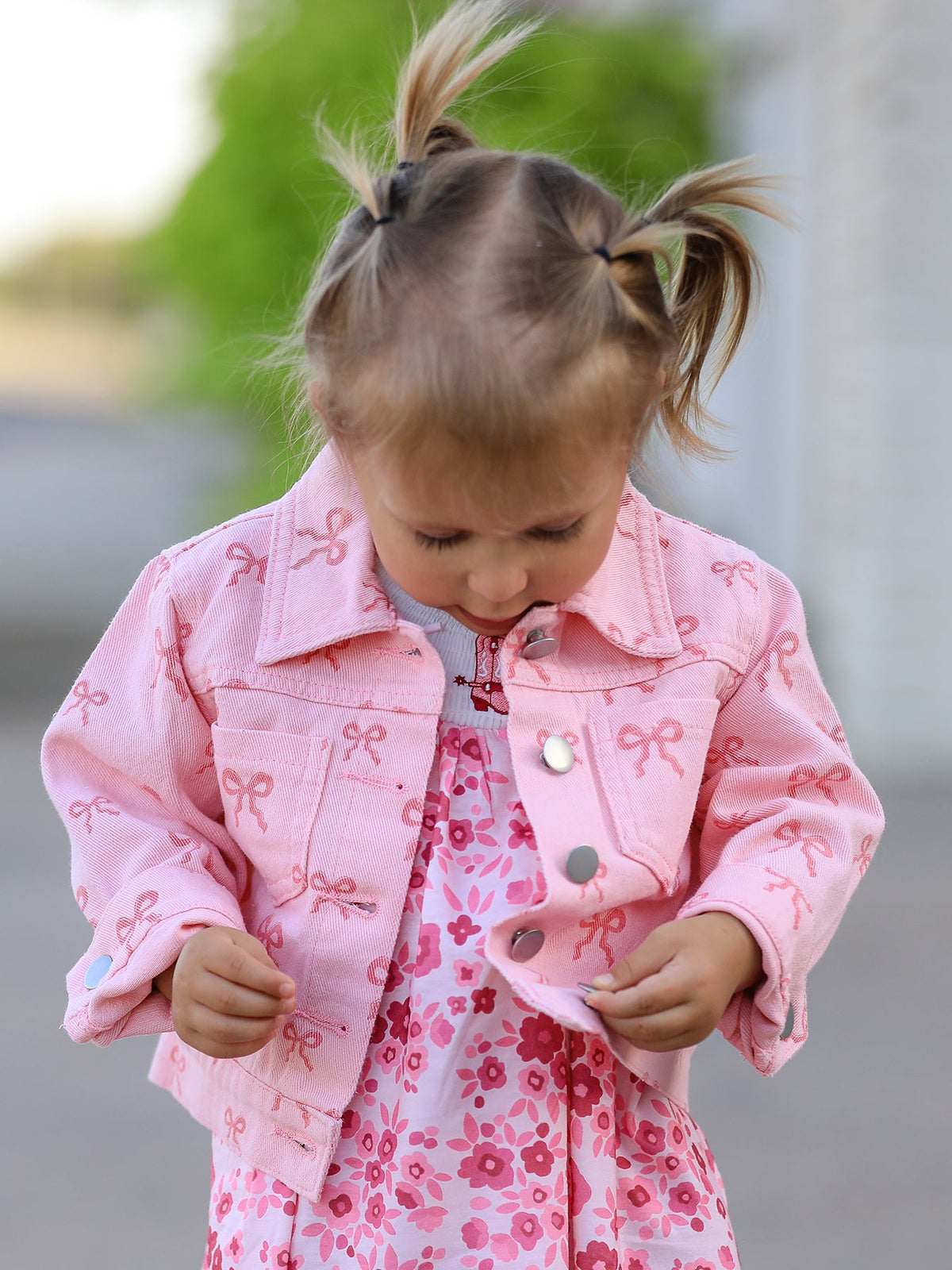 Toddler girl wearing pink girls butterfly denim jacket by Rylee Faith Designs with bow print and floral dress