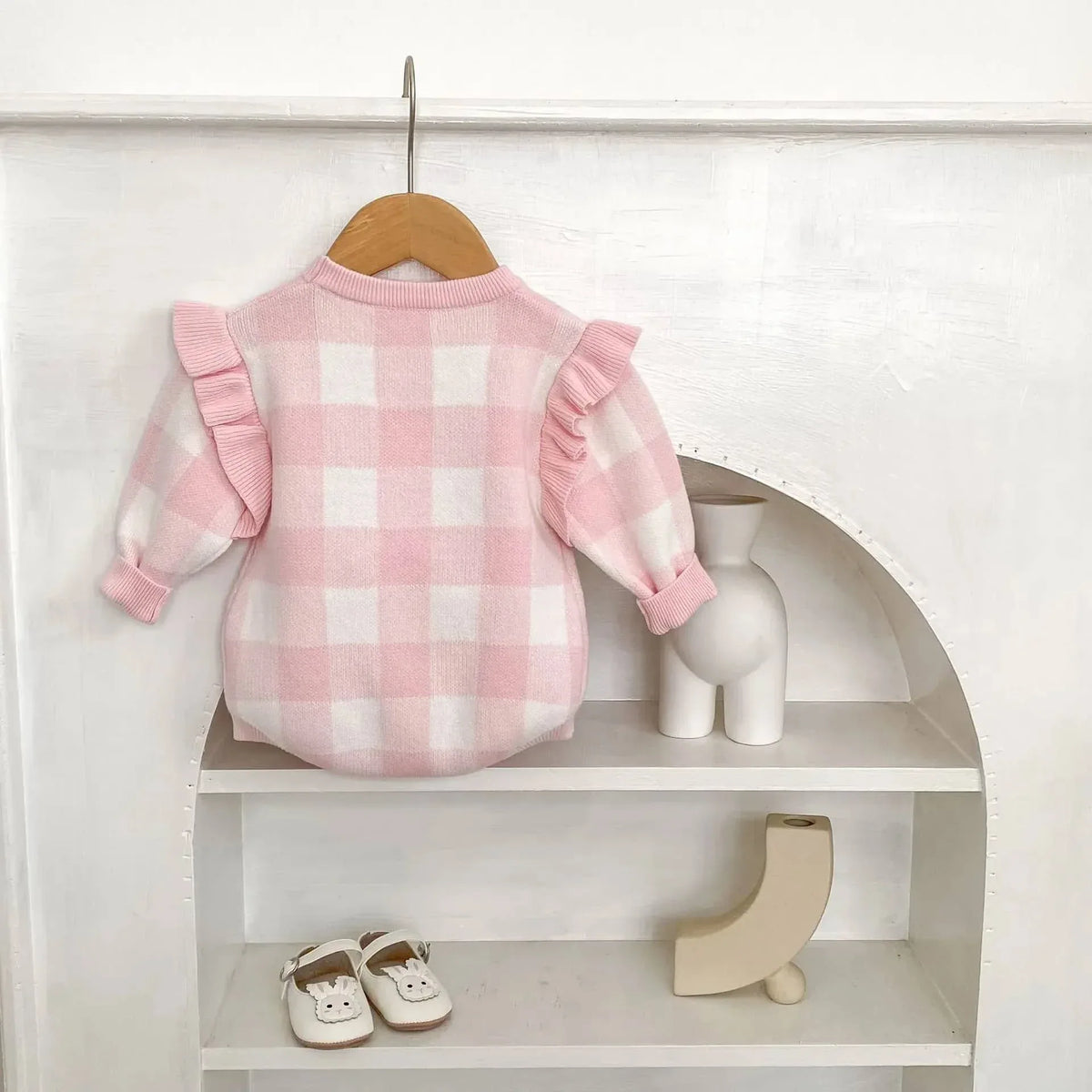 pink plaid baby romper with ruffle sleeves for infants displayed on wooden hanger