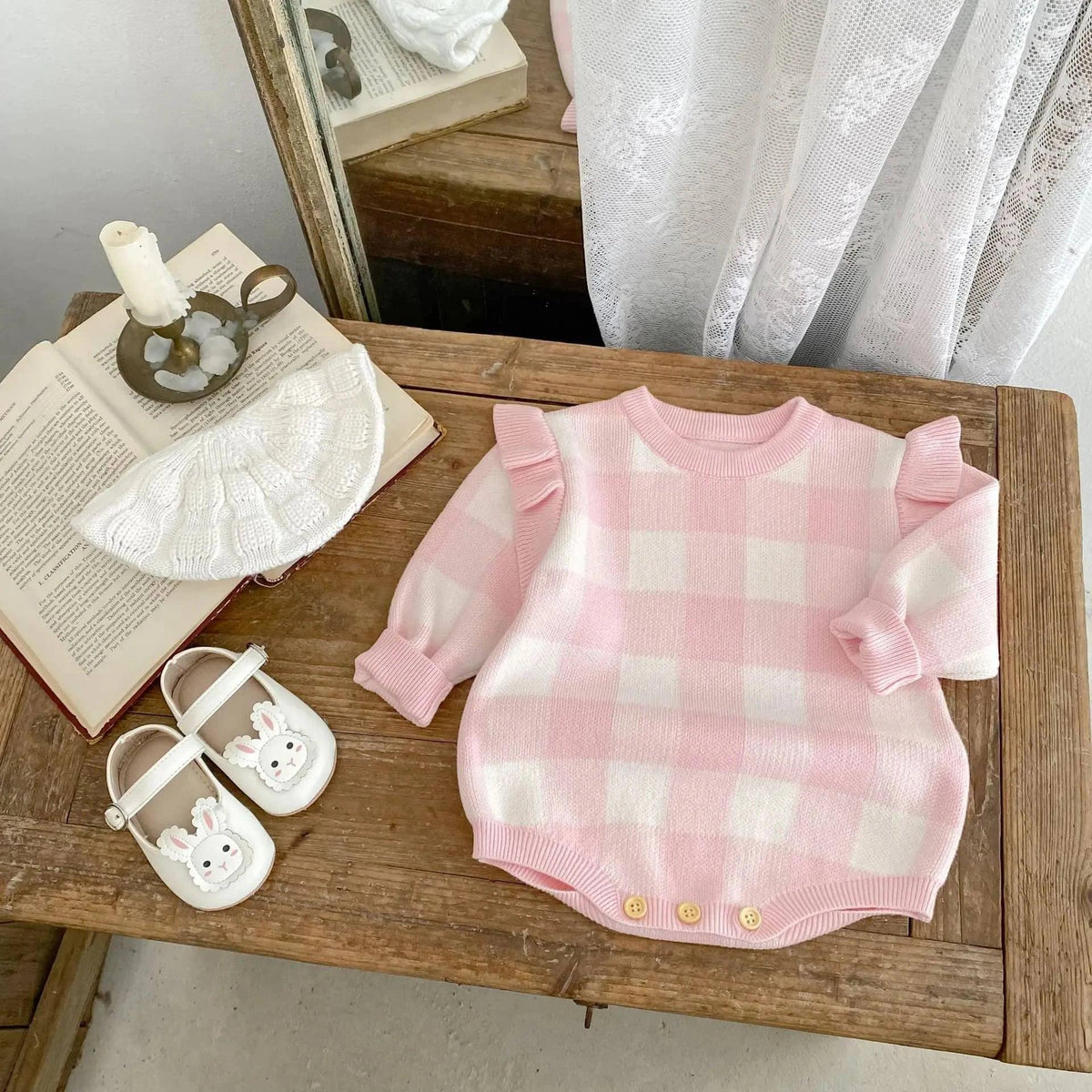 pink plaid baby romper with ruffle sleeves for infants displayed on wooden table