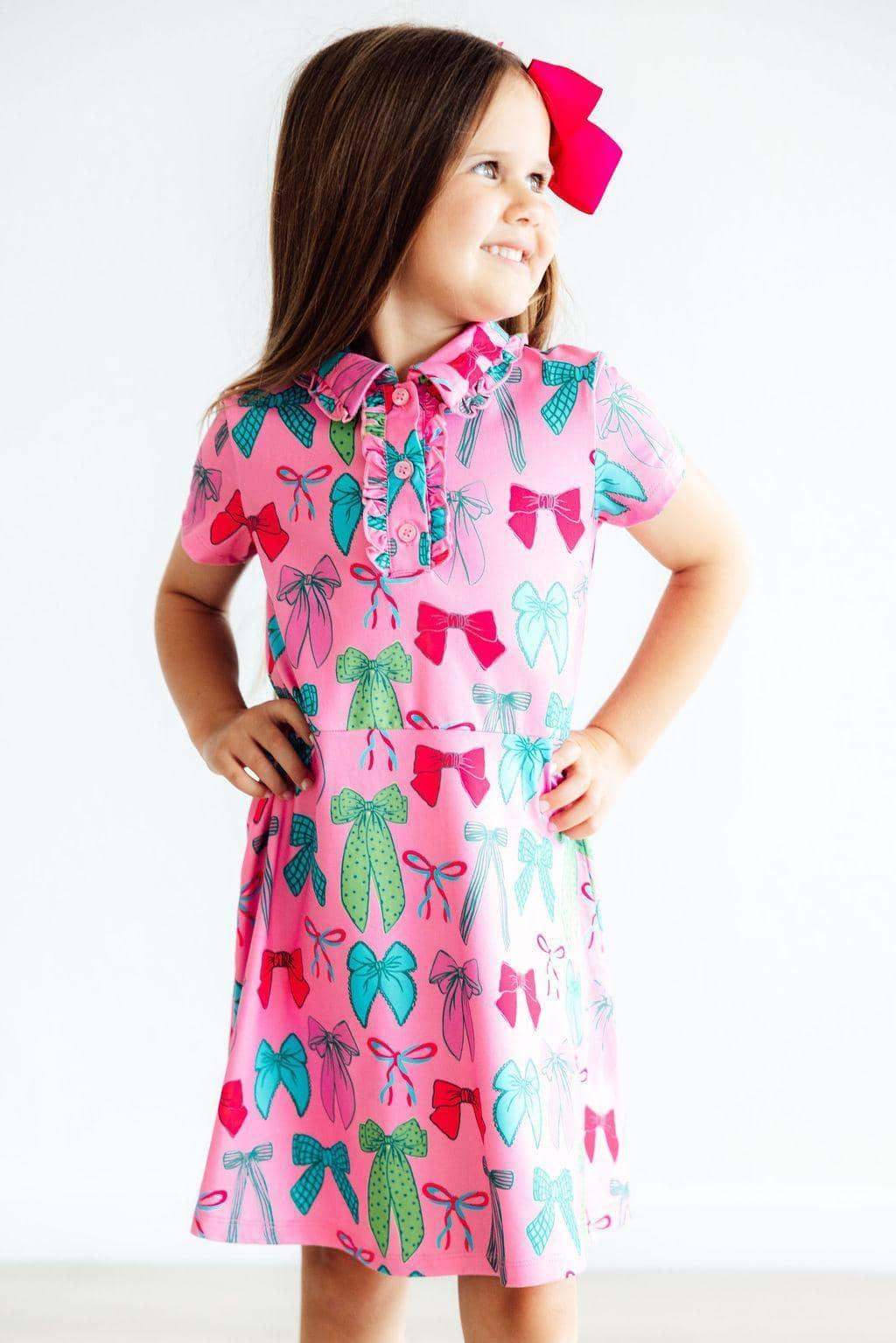 Pink polo dress for girls with colorful bow print, short sleeves, and collar, perfect for young children