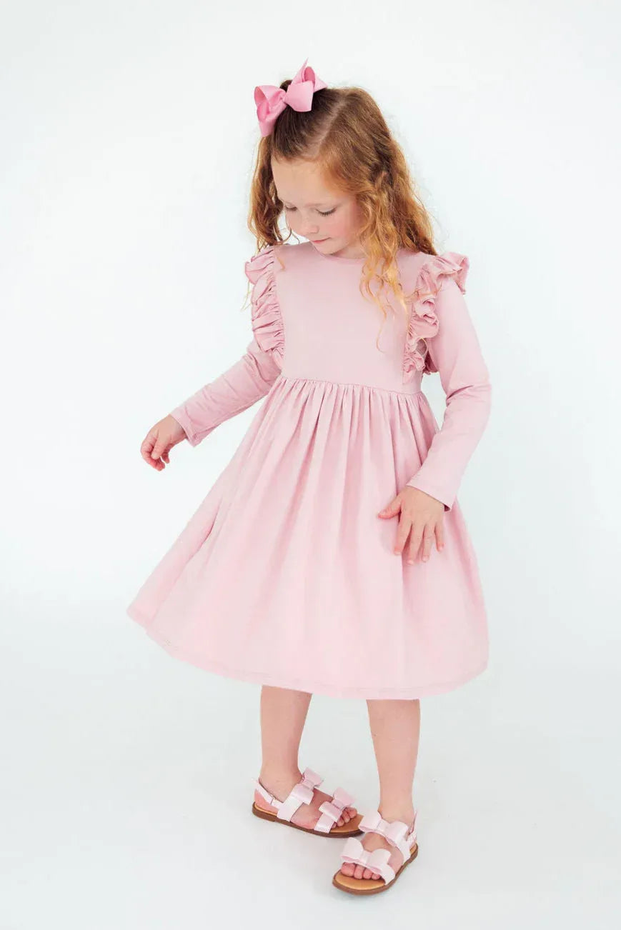 young girl wearing pink ruffle twirl dress for girls standing and looking down