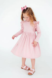 young girl wearing pink ruffle twirl dress for girls standing and looking down