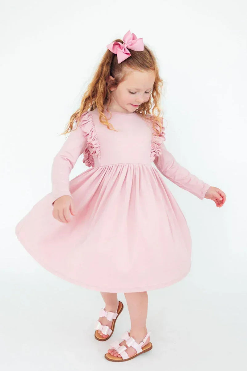 Young girl wearing pink ruffle twirl dress for girls with long sleeves spinning and smiling