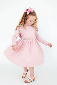 Young girl wearing pink ruffle twirl dress for girls with long sleeves spinning and smiling