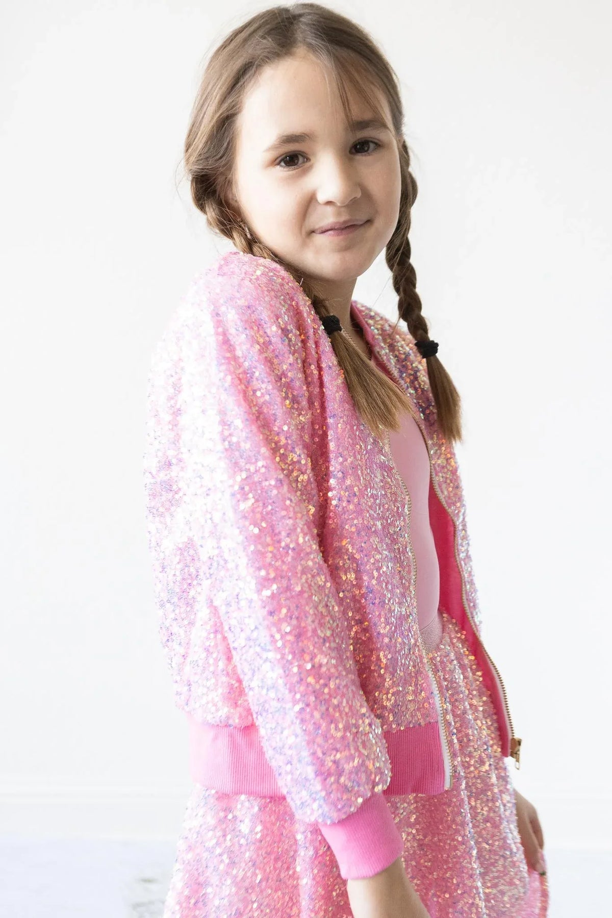 girl wearing pink sequin jacket for girls with braided hair standing and smiling