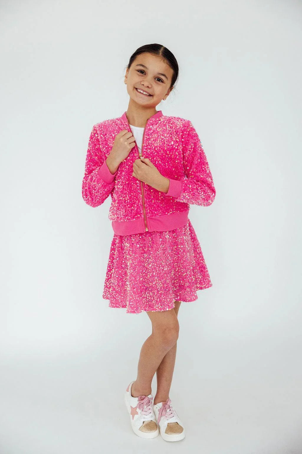 Girl wearing pink sequin jacket for girls and matching skirt smiling and posing